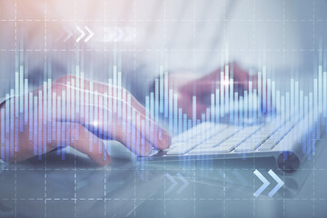 Double exposure of graph with man typing on computer in office on background. Concept of hard work.