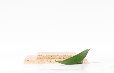 White product presentation scene, product mockup, front view. Made with natural stone travertine and green leaf.