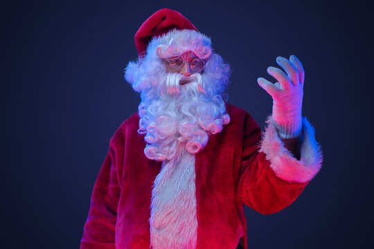 Portrait of santa claus dressed in red costume posing with his hand.