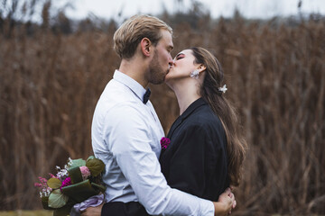 Young married couple, husband kissing his wife. Outdoor wedding photoshoot. High quality photo