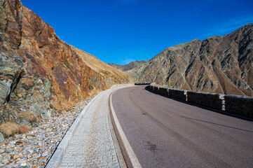 Asphalt road high in the mountains with rocky peaks.