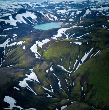 Aerial View over Mossy Mountains & Hidden lake formed by volcanic eruptions in the Icelandic Highlands, Landmannalaugar, Iceland