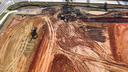 Busy heavy machines working on earthmoving works for raft foundation of large warehouse...