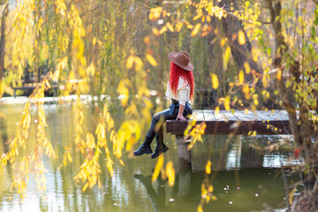 Autumn lake woman. She sits by a pond on a wooden pier in autumn and admires nature. The concept of...