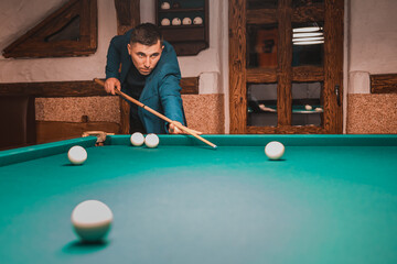Fototapeta premium Playing billiards, a man as an amateur plays billiards, a sports board game.