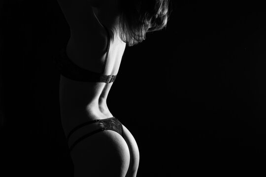 Young sexy Woman black and white photo. Seductive young woman in darkness. Glamour lady with posing in spotlight.