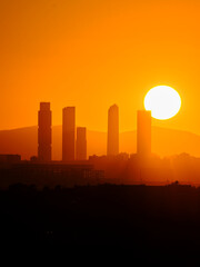 Fototapeta na wymiar Madrid city skyline in silhouette sun and mountains on background five towers bussiness area skycrapers