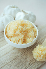 close up of minced garlic on a wooden spoon 