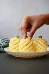 hand pick slice of pineapple in bowl on table 