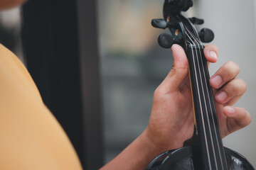 A Little Asian kid playing and practice violin musical string instrument against in home, Concept of Musical education, Inspiration, Teenager art school student. © Prot