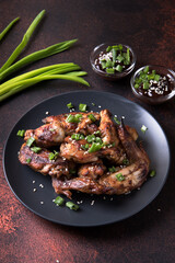 Barbecue chicken wings on a dark red background.