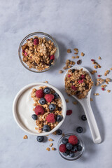 Yogurt with granola and fresh berries on a marble background.