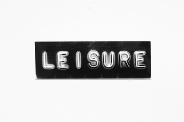 Black color banner that have embossed letter with word leisure on white paper background