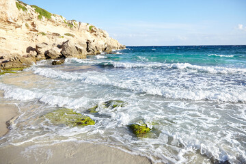 Sand beach, summer sea with blue sky. Sea water with rocks and white waves. Cala azzurra beach, Favignana island, Province of Trapani, Sicily, Italy. A beautiful seascape