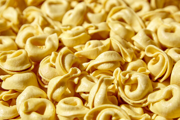 Tortellini pasta with prosciutto food background. Italian stuffed pasta
