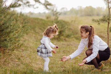 Naklejka na ściany i meble beautiful and happy mother and daughter have a good time in the forest