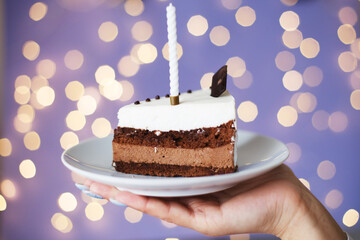 woman holding piece of cake with a candle