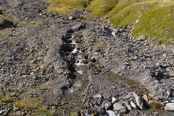 Scenic view of famous Swiss mountain pass Furkapass with rocks and creek on a sunny late summer day. Photo taken September 12th, 2022, Furka Pass, Switzerland.