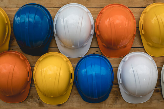 Close-up, multi-colored construction helmets for engineering and worker construction site hanging on an old wooden wall