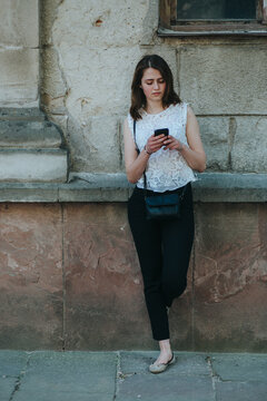Happy beautiful young Caucasian girl with smart phone outdoors on sunny summer day texting and smiling