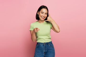 Beautiful brown haired woman standing with call gesture, looking and pointing