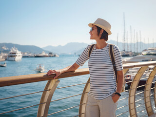 Marmaris is resort town on Turkish Riviera, also known as Turquoise Coast. Marmaris is great place for sailing and diving. Asian woman with hat walking on pier in harbor.