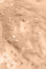 Cosmetic liquid with bubbles texture on beige background. Skin care