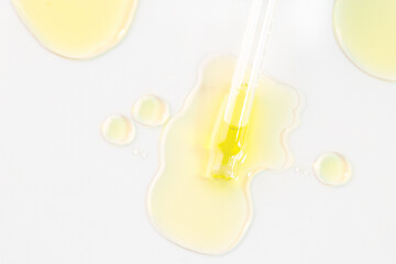 Dropper pipette with oil serum liquid  and smear drops on white background .Flat lay