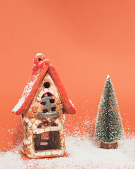 House and tree decorated with snow on sandy brown background. Creative Winter season concept with copy space. Warm Christmas holiday idea.