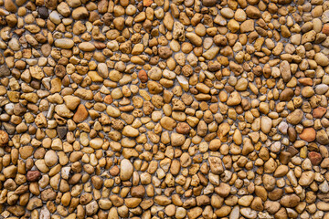 Natural background wall with beige and brown pebbles and stones
