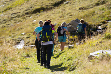 Women hiking group way up to Swiss mountain pass Furkapass on a sunny late summer day. Photo taken...