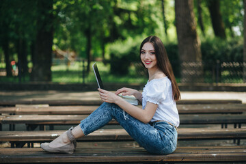Obraz premium Young woman with smartphone and laptop on the bench