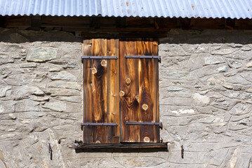 Closed wooden shutters at abandoned traditional building at mountain hamlet Gletsch, Canton Valais, on a sunny late summer day. Photo taken September 12th, 2022, Gletsch, Switzerland.