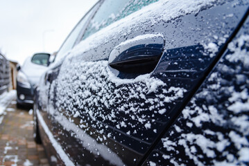 Snow covered handle of the driver's door of the car.doors and handles covered with snow and frost.winter driving,preparing for the trip.Black car coated snow crust during the icy rain in cold weather.