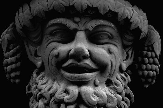 Face of god of wine, fun and entertainment Bacchus (Dionysus). Black and white image. Fragment of an ancient statue.