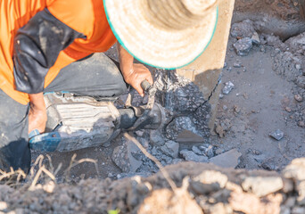 A worker with a jackhammer breaks concrete pilesl.