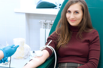Donor donates blood in medical clinic. Beautiful European woman of 30 years sits in medical chair...