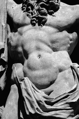 Fragment of an ancient stone statue of Hercules as symbol of power and strength. Black and white horizontal image.