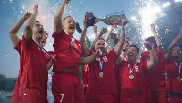 Football Finals Tournament Winning Team Celebrates Victory Cheering and Lifting Trophy Prize on Stadium. Happy Soccer Players Champions of International Championship Cup. Slow Motion Fireworks Shot