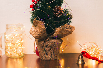 A Christmas tree and a bell with a red ribbon. Christmas lights in the background. Beautiful Christmas or New Year background. Merry Xmas. December. Symbols of winter holidays