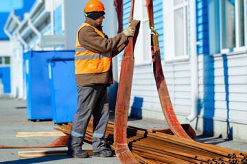 Slinger stacks thin metal pipes in stack on construction site. Close-up. Real workflow. Unloading...