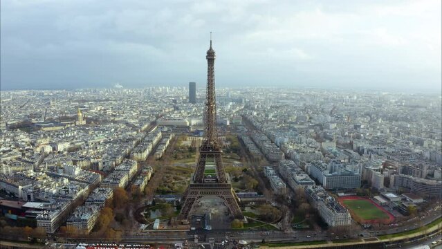 Panoramic aerial view of Eiffel Tower or Tour Eiffel iconic historical landmark is a wrought iron lattice high tower with drone panorama above view of Champ de Mars landscaped park in Paris, France