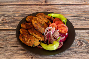 Fried vegetable patties on a plate. Homemade meatballs made of cauliflower garnished with fresh tomatoes, peppers and onions. Vegetarian lunch or dinner idea.vegetarian meatballs