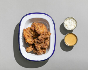 Fried chicken in kentucky style on metal plate with sauces