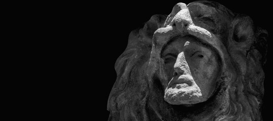 Hercules wearing Nemean lion skin. Fragment of an ancient stone statue against black background....