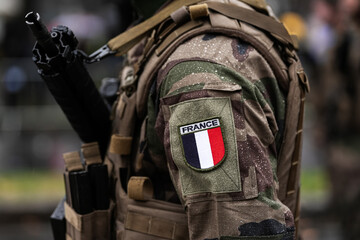 France Army soldiers uniform. Close up photo with the France flag on a military soldier uniform with the gun next to it. Military industry concept photo.