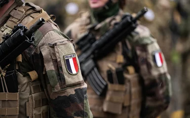 Poster France Army soldiers uniform. Close up photo with the France flag on a military soldier uniform with the gun next to it. Military industry concept photo. © Dragoș Asaftei
