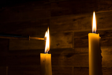 A burning candle on a dark background and a model of military equipment in the background