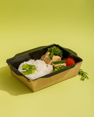 Fototapeta na wymiar Healthy boiled rice with steamed turkey, broccoli and tomatoes in cardboard box closeup for delivery