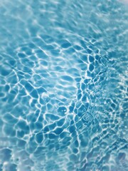 Defocus blurred transparent blue colored clear calm water surface texture with splashes and bubbles. Trendy abstract nature background. Water waves in sunlight with copy space. Blue watercolor shining